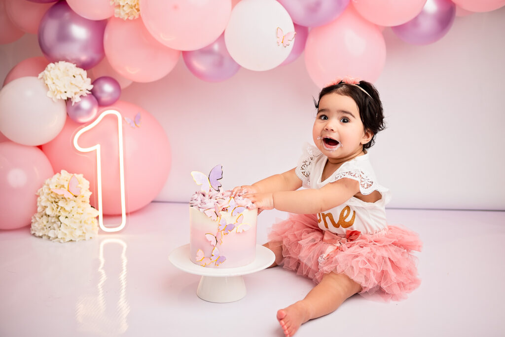 baby girl smashing a cake during her cake smash photoshoot at Ola Molik Photography Studio in Glasgow