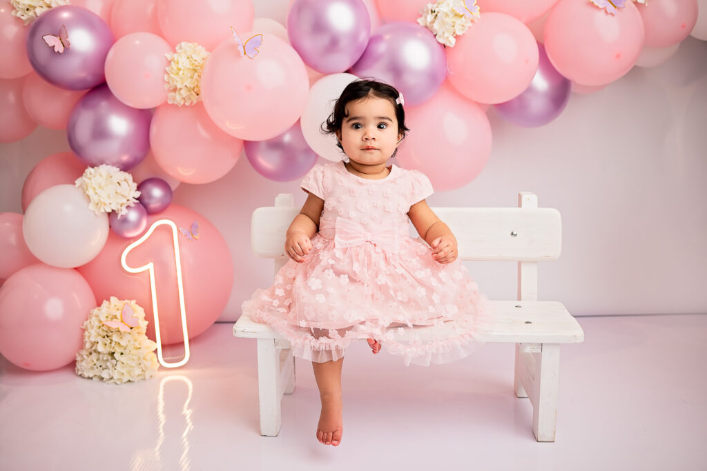 baby girl sitting at the bench during her first birthday cake smash photoshoot at Ola Molik Photogrpahy Studio
