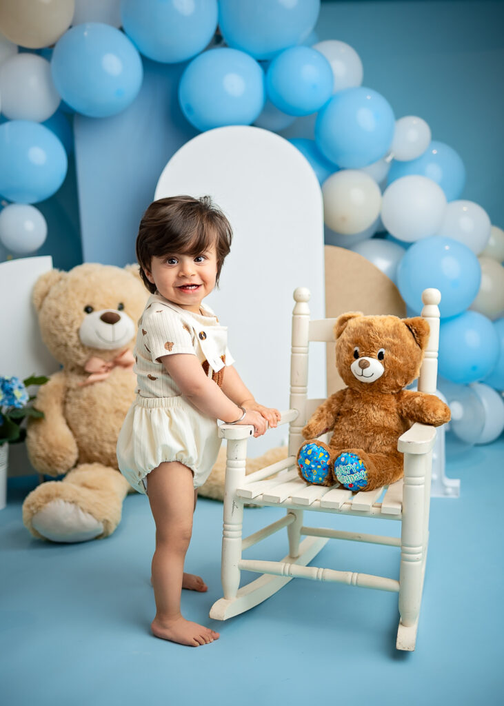 baby standing and holding a wooden chair during Teddy Bear Cake Smash in Glasgow