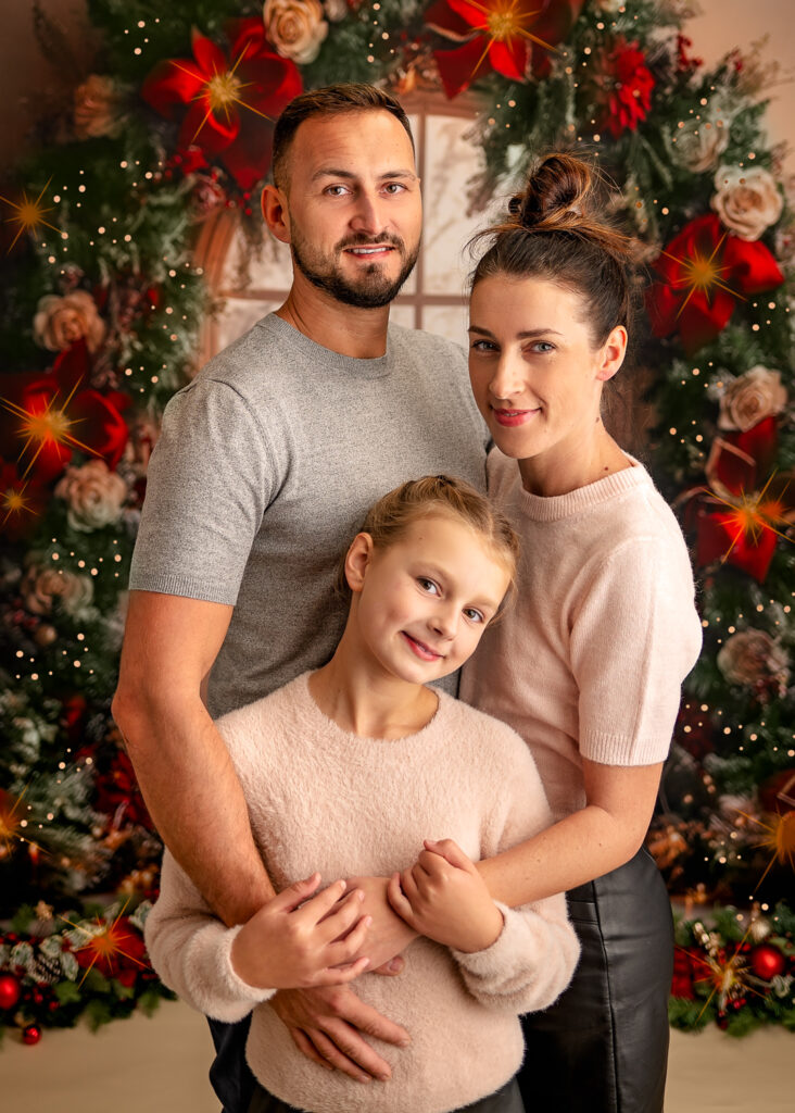 Family cuddling and posing on the beautiful Christmas background in photography Studio Ola Molik Photography